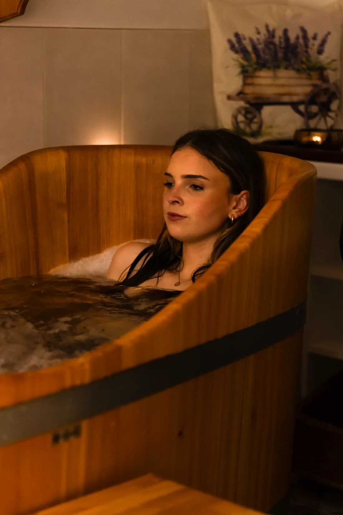Hostka odpočívá v dřevěné koupelové kádi v soukromém wellness